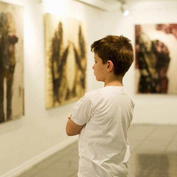 9 years old boy visiting an art gallery and looking to the paintings…